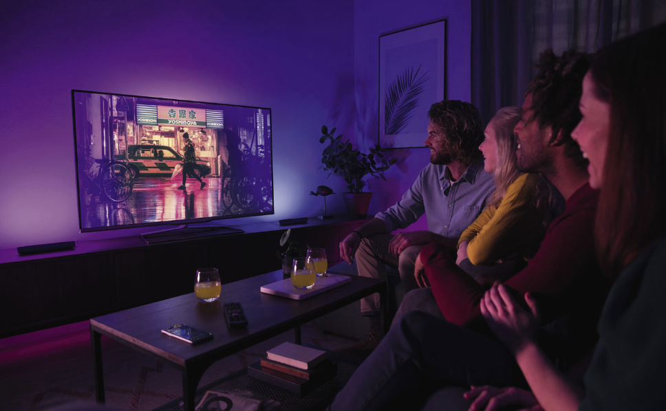 Four friends watching TV with Philips lighting.