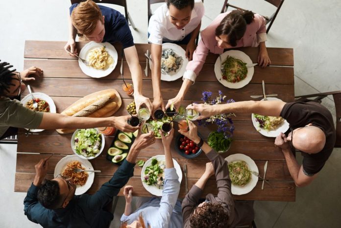 image of a group clinking glasses over a dinner table