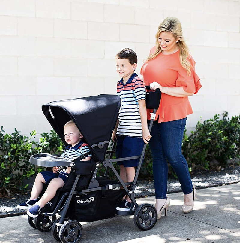 Woman with young boy and child in a tandem double stroller.