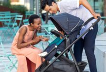 A woman crouching to look at a baby in a stroller a man is pushing.