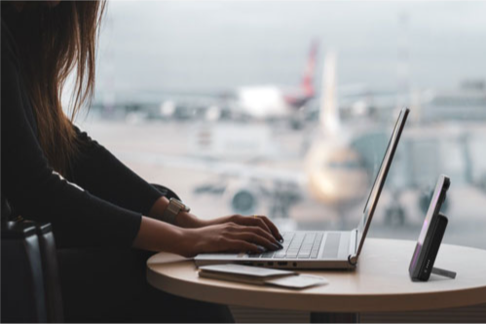 Femme qui recharge son téléphone à l'aéroport avec un chargeur portable sans fil.