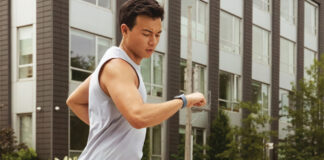 A man running and looking at his smartwatch.