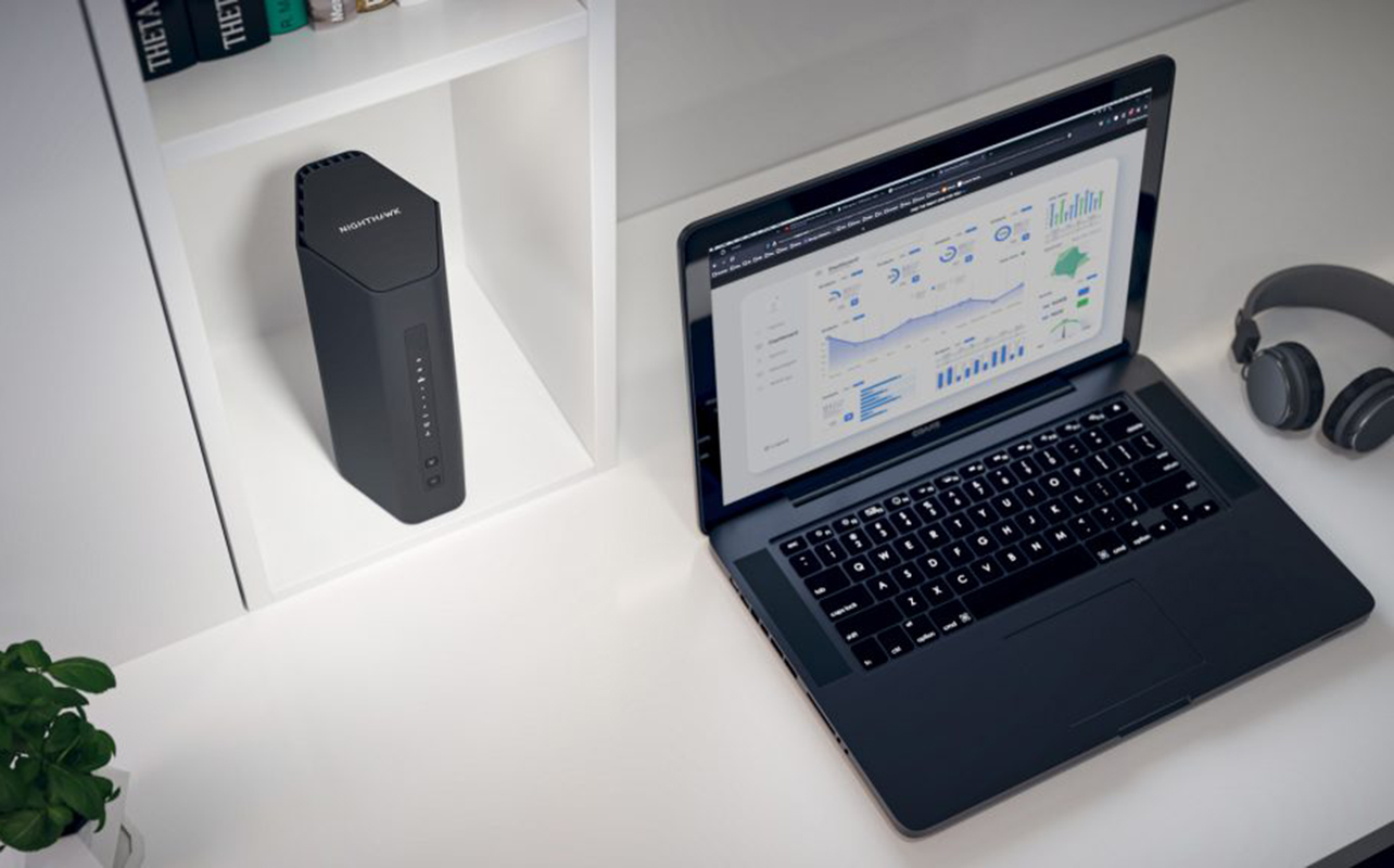 Routeur Wi-Fi posé à côté d'un portable sur un bureau.