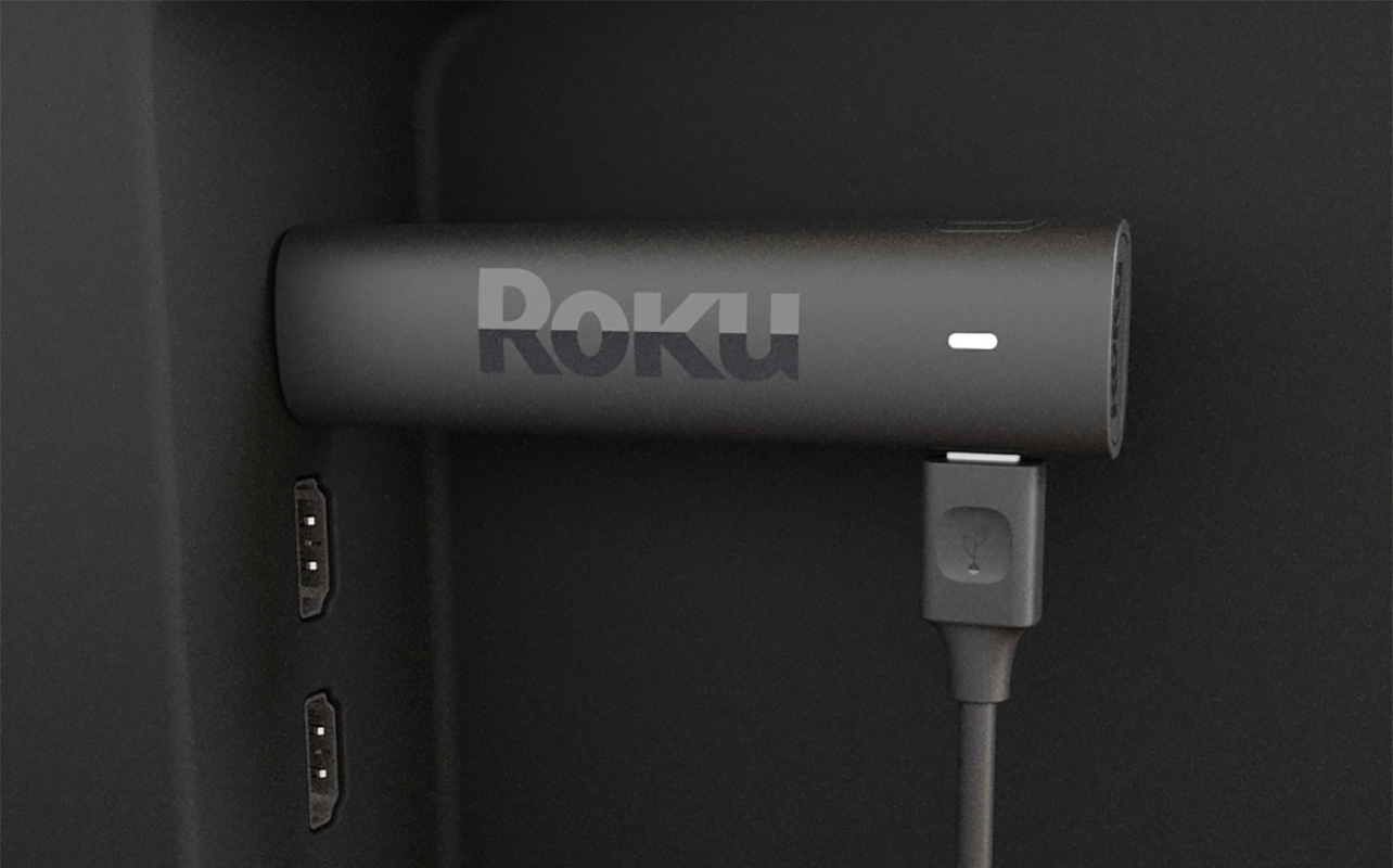 A Roku streaming stick plugged into the side HDMI port of a TV.