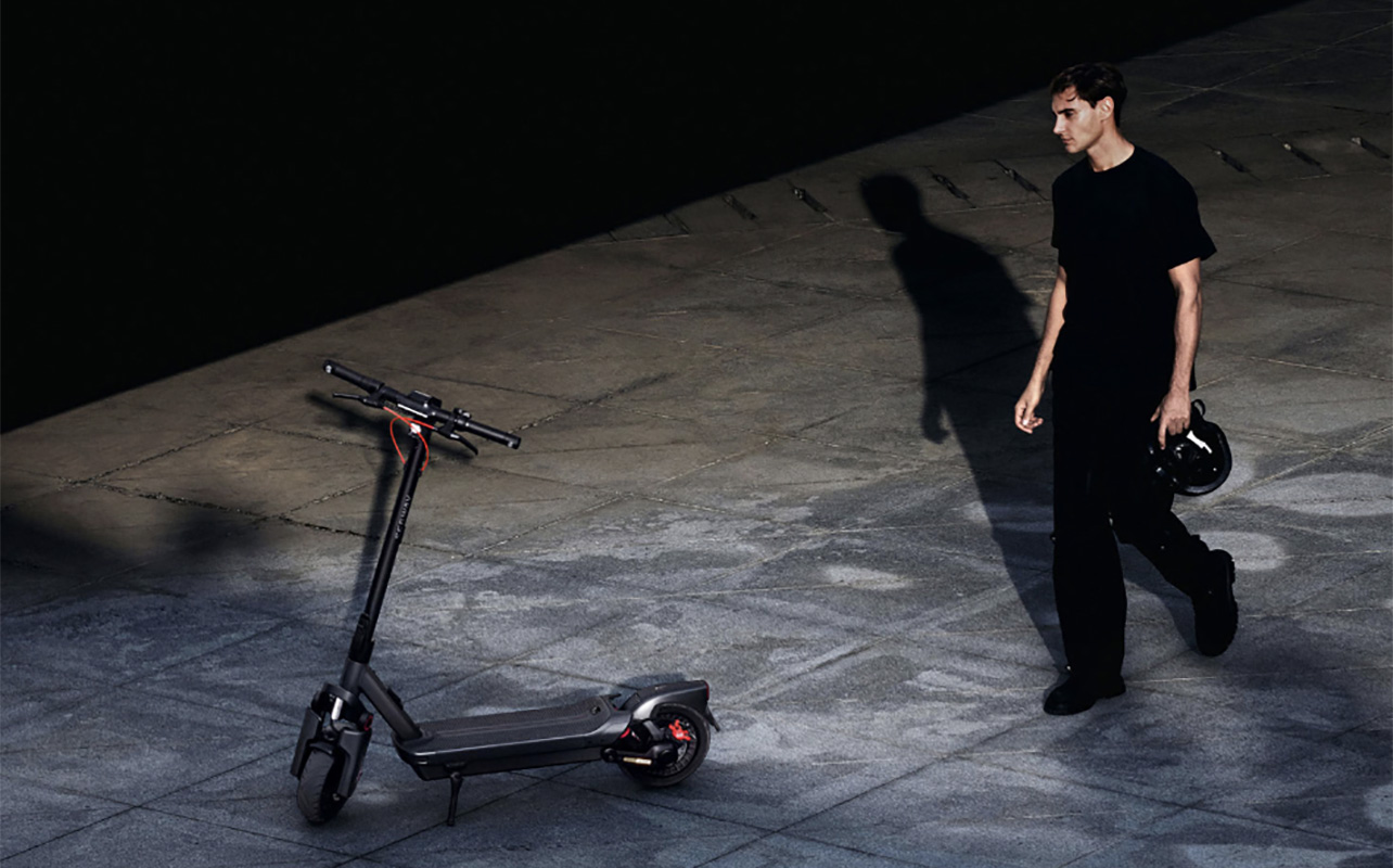 Un homme marche vers une trottinette Max G3 de Segway dans le noir.