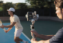 Man using camera on gimbal to track tennis player.