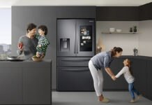 A family in the kitchen with the Samsung Family Hub fridge behind them.