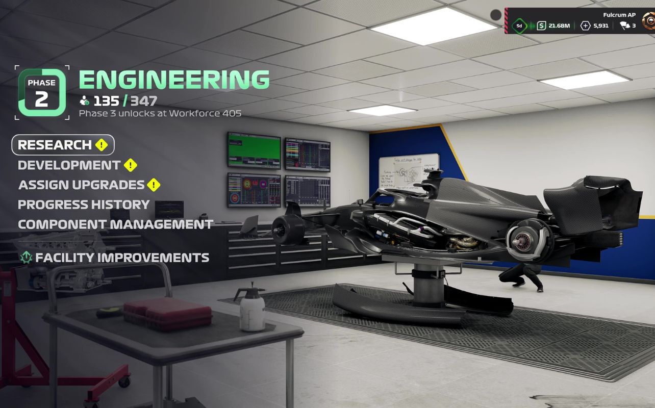 An in-game screenshot from F1 25's My Team mode, depicting the Engineering facility with a Formula 1 car elevated on a hydraulic hoist. The scene showcases the game's enhanced graphics, including detailed garage equipment, realistic lighting, and a well-lit workspace. The car's intricate components are visible as well.